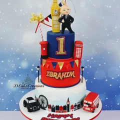 A three-tier London-themed cake for Ibrahim's first birthday, featuring a "Boss Baby" style figurine, Big Ben, and a classic red bus.