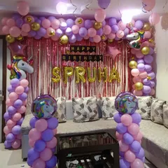 A classic unicorn theme featuring a full balloon arch in pink and purple with gold accents. The setup includes unicorn foil balloons on the arch and pillars, set against a pink shimmer curtain for a magical birthday atmosphere.
