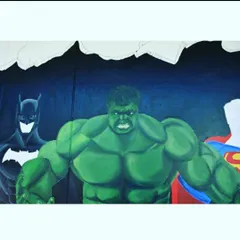 Bringing heroes to life. This mural features Batman, Hulk, and Superman bursting through a wall, creating a powerful and exciting piece for a themed space.