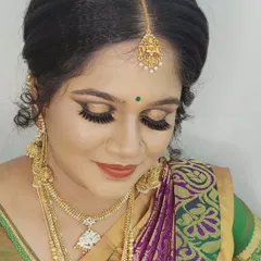 A close-up of a traditional South Indian bridal makeup look. You can see the detail in the golden shimmer eyeshadow, thick lashes, and the perfectly placed maang tikka, all essential for the muhurtham ceremony.