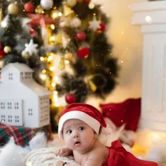 The most precious Christmas gift. This newborn is peacefully posing in front of a beautifully lit Christmas tree, a perfect memory for their first holiday season.
