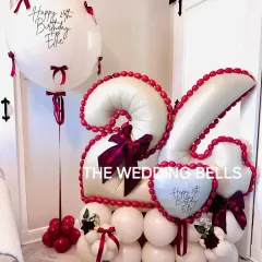 Celebrating a 25th birthday in style. This custom balloon arrangement features the number '25' in elegant white and red, detailed with bows and a personalized jumbo balloon. We can create this in any color scheme and for any age.