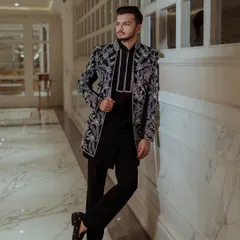 A confident, full-length portrait of the groom in his striking black and silver embroidered Sangeet jacket.