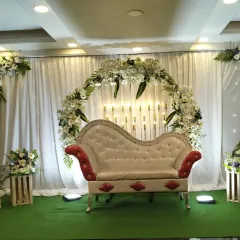 A sophisticated engagement decoration with a white and green color scheme. The floral arch, corner bouquets, and rustic wooden crate props create a chic and modern look.