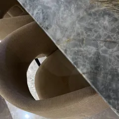 An overhead shot of a dining chair with beige corduroy upholstery next to a grey marble dining table, highlighting the contrast of soft and hard textures.
