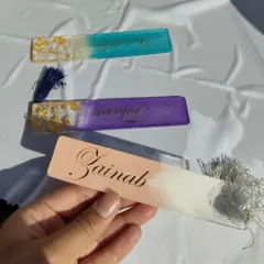 A set of three custom name bookmarks I created. Each one has a unique color combination, from teal and gold to purple and gold, showing the range of personalization available.