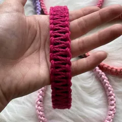 A close-up view of a vibrant magenta macrame hairband held in my hand. This angle highlights the consistent, tight knotting I use to create a durable and comfortable hair accessory.