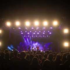 This image captures the concert experience from within the audience, showing the crowd's view of the stage lit up in vibrant purple hues.