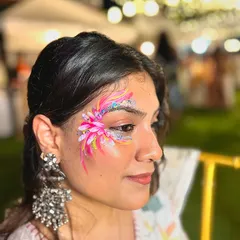 This vibrant pink floral piece is a great example of using bright colors and glitter to create a festive look. Notice how the design flows along the side of the eye, enhancing the client's features.