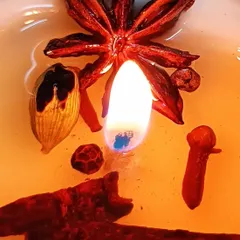 A close-up of a lit aromatherapy candle, showing the excellent fragrance release, or 'hot throw'. This one features a warm blend of whole spices like star anise, cinnamon, and cloves, creating a rich and comforting scent.