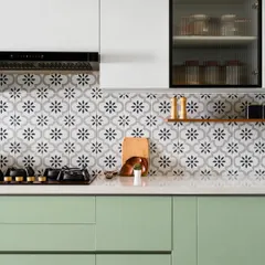 We call this the 'Garden of Eden' kitchen for its fresh green cabinetry, patterned floral tiles, and warm veneer accents. The combination of colors and textures creates a vibrant and refreshing culinary space.