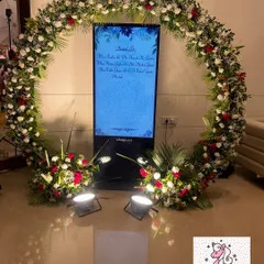 A modern and interactive welcome for your guests. This digital welcome screen is framed by a beautiful circular floral arch, combining technology with classic decor.