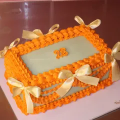 A celebration in itself. This rectangular cake features bold orange Lambeth-style piping and is adorned with delicate golden ribbons for an elegant finish.