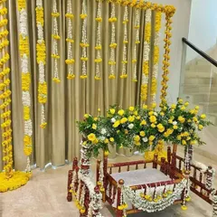 This is a traditional jhula (swing) decoration for a baby naming ceremony or Janmashtami pooja. I used bright yellow marigolds and white flowers to create a festive backdrop and adorn the wooden jhula itself.