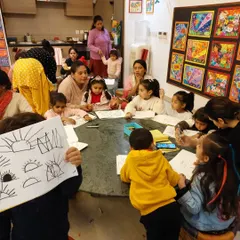 A teacher demonstrates a drawing technique to an eager group of toddlers. We use simple, recognizable shapes to build their drawing confidence.