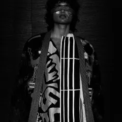 Continuing the conceptual narrative, this shot plays with texture, pattern, and shadow. The blindfold and abstract clothing challenge the viewer, making it a memorable piece of fashion art.