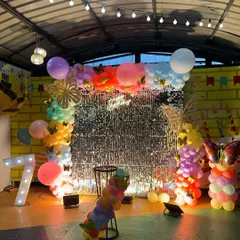 This butterfly-themed party features a rainbow of balloons against a silver shimmer wall, creating a vibrant and sparkling effect.