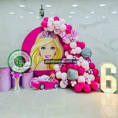 This Barbie party features a large character graphic on a round backdrop, a pink convertible car cutout, and a light-up number '6'. The disco ball balloons add a touch of sparkle and fun.
