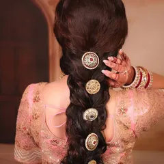 A close-up of a stunning bridal braid. This hairstyle is decorated with large, traditional, kundan-style hair accessories, adding a regal and unique touch to the overall look.