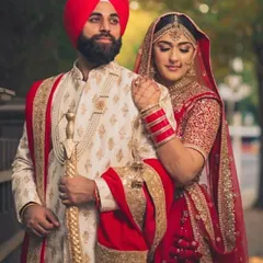 Another view of our popular red and beige coordinated set. Notice the detail on the groom's sherwani, including the pearl necklace and matching stole, which ties the entire look together with the bride's red lehenga.