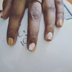This design on short nails combines sparkly gold glitter with a modern, geometric color-block pattern in nude and white for a stylish and eye-catching look.