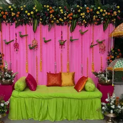 Here is a closer view of our pink and green Haldi seating area. The setup includes a comfortable low sofa with colorful cushions, decorative bird hangings, and Rajasthani umbrellas, perfect for photo opportunities.