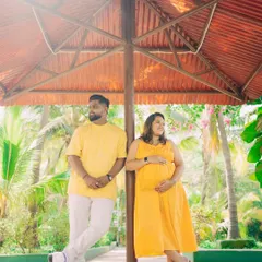 Finding interesting structures in an outdoor location can add a unique touch to your photos. Here, the couple poses under a shaded gazebo, creating a relaxed and stylish portrait during their maternity session.