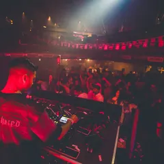 A view from behind my shoulder at FLO, showing my focus on the decks as I mix for a packed club under the red lights.