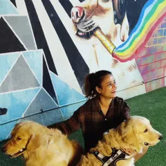 Two beautiful Golden Retrievers posing on the turf in front of another one of our unique art pieces.