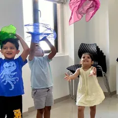 Joy is a key ingredient in our classrooms. Here, children are tossing colourful scarves in the air, an exercise that helps them visualize musical phrases and experience the feeling of high and low pitches through movement.