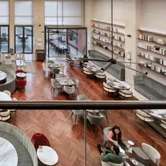 An overhead view of the Elevate Clubhouse shows the dynamic interplay between the two levels. The mezzanine balcony overlooks the main dining area, creating a strong visual connection and enhancing the sense of a large, unified community space. The layout encourages movement and interaction, making the entire clubhouse feel alive.