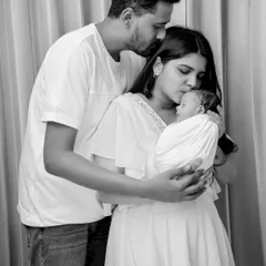 A tender black and white moment where both parents are kissing their newborn's head. This image beautifully captures the overwhelming love and affection in a new family.