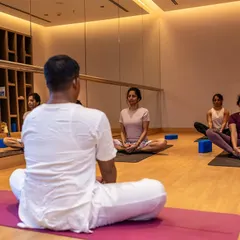 An instructor guides a Hatha yoga class in our indoor studio. The mirrored wall helps participants refine their alignment, while the calm, focused environment is perfect for deepening your practice regardless of the weather.