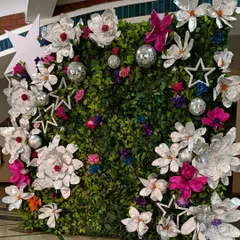 A photo backdrop should be a work of art. I designed this chic and modern photo wall using a lush green foliage base, accented with oversized, handcrafted paper flowers and sparkling disco balls for a touch of glamour.