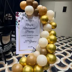 A personalized welcome sign is a wonderful touch for any milestone event. This one, for Rosy's retirement party, was framed by a beautiful organic balloon garland in a classy gold, white, and brown palette.