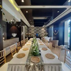 This wide-angle view shows the complete long-table dinner arrangement within the venue. We ensure every element, from the chair placement to the overall room layout, contributes to a cohesive and polished event design.