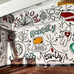 The finished doodle mural for a CA students' hostel, filled with words like "Wisdom," "Honesty," and "Empathy," alongside icons of success and hard work.
