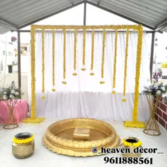 A simple yet beautiful Haldi setup on a rooftop, featuring a frame of bright yellow marigolds and a large brass urli. This design is perfect for intimate, at-home ceremonies.