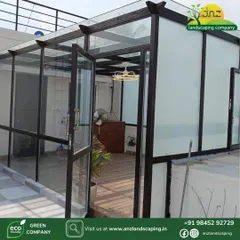This is an all-weather glass sunroom we built for a client in Bengaluru. It features a robust powder-coated steel frame, a mix of clear and frosted toughened glass for privacy and light, and elegant wooden flooring, creating a comfortable year-round living space.