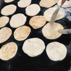 Fresh parathas being cooked on a large tawa. We make our breads live on-site whenever possible to ensure they are served soft and hot, perfect for pairing with our curries.