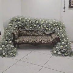 For an intimate engagement ceremony at home, I decorated this sofa with a beautiful arch of baby's breath and white roses, turning a simple space into a special photo spot.