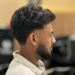 A fresh fade with sharp edges on a client with curly hair. This cut is clean, stylish, and turns heads.