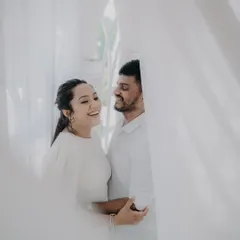 A soft and dreamy shot taken through sheer white curtains. This creative technique adds a layer of intimacy and romance to the couple's portrait.