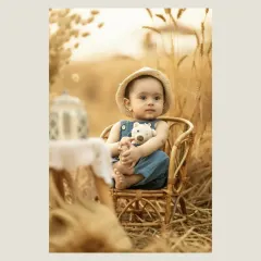 A closer portrait of the child in the wheat field, holding a small teddy bear. His curious and innocent gaze is the focus here, with the soft, golden light beautifully illuminating his features.