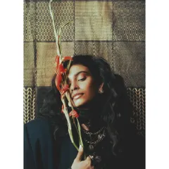 A tender moment from 'Roots', where the model holds a flower to her face. This image introduces a natural, organic element, connecting personal growth to the resilience of nature.