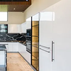 This view highlights the full-height, integrated appliances and the smoked glass pantry, which is internally lit to showcase its contents.