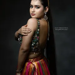 A stunning look for a Sangeet or reception, featuring a heavily embellished blouse and a multi-colored lehenga. The makeup is kept glamorous with a focus on defined eyes and contoured features.