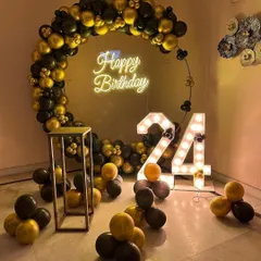 A stylish black and gold theme for a 24th birthday. The circular balloon arch and light-up numbers create a sophisticated photo corner.