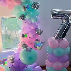 A closer look at the butterfly theme balloon pillar and arch. The mix of pastel pink, purple, and mint green balloons with silver accents creates a magical look for a girl's birthday.