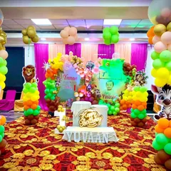A vibrant and fun jungle theme birthday party. The stage is filled with colorful balloon pillars, cutouts of jungle animals like lions, zebras, and rabbits, and a personalized "Happy Birthday Yuvaan" sign.